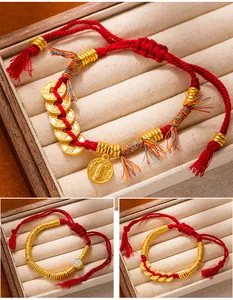 Detail views of three styles of traditional red string bracelets with gold-tone coin charms