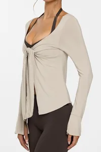 Gros plan d'un cardigan de yoga montrant le détail du nœud et la coupe ajustée beige