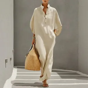 Élégante robe longue en lin beige avec col boutonné dans un décor extérieur ensoleillé