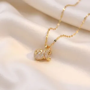 Gold lucky money bag necklace with pavé zirconia stones on soft silk background