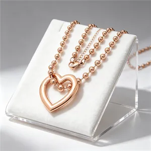 Close-up detail of rose gold hollow heart pendant necklace on white velvet display stand