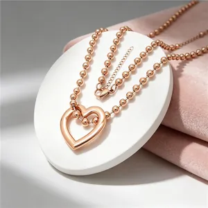 Close-up of rose gold heart pendant necklace on bead chain with pink velvet background