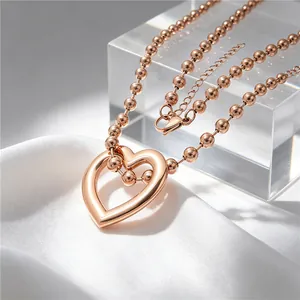 Close-up of rose gold stainless steel heart pendant necklace on white silk and acrylic.