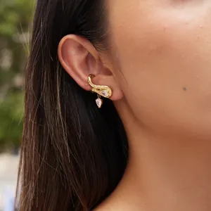Detalle de un ear cuff de acero de titanio dorado con circonitas en forma de pera