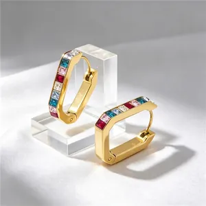 Macro view of gold U-shaped hoop earrings featuring colorful baguette zircons.