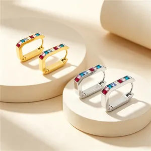 Close-up detail of gold and silver U-shaped earrings with colorful rectangular CZ inlay