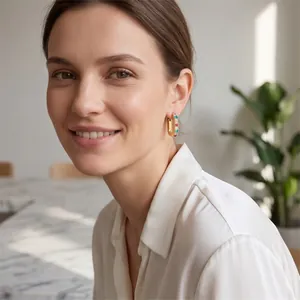 Detailed shot of a woman wearing gold-plated U-shaped earrings with colorful zircons