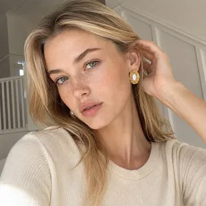 Model wearing gold-plated stainless steel oval stud earrings with pearl center