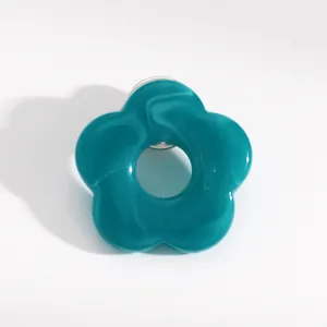 Detail macro view of a stylish teal marbled resin hollow flower brooch and eyeglass holder pin.