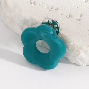 Close-up detail of a minimalist teal hollow flower brooch and glasses holder pin on stone