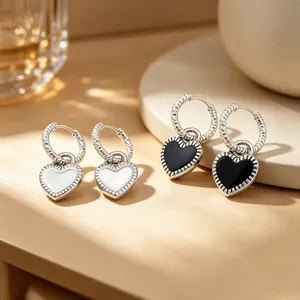 Gros plan de boucles d'oreilles cœur en émail noir et blanc sur support en pierre