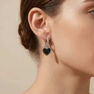 Détail macro d'une boucle d'oreille en émail noir en forme de cœur sur un mannequin
