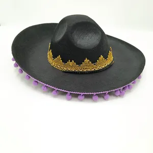Close-up of black Mexican party hat with gold lace and purple pom-poms decoration.
