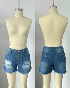 Detail view of women's distressed blue denim shorts with raw hem and button fly.