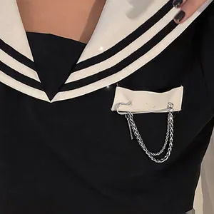 Detailed macro shot of a silver safety pin brooch featuring a double chain on a sailor uniform