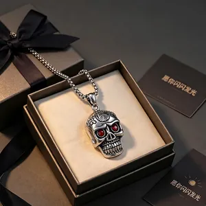 Détail d'un collier pendentif tête de mort vintage en acier titane aux yeux rouges dans un coffret
