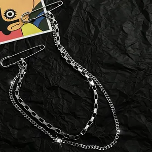 Detailed view of silver layered chain accessory with safety pin fasteners on black background.