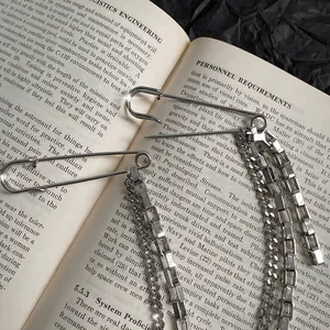 Close-up detail view of silver long chain safety pin brooch in hip-hop street style