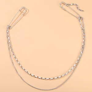 Macro view of a silver double-layered chain brooch with safety pins for streetwear
