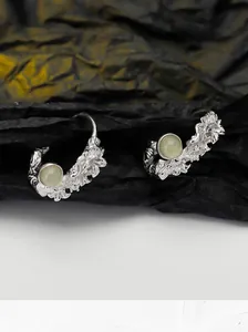 Close-up of S925 sterling silver floral earrings with a round pale green stone inlay
