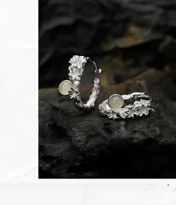 Detailed macro view of S925 sterling silver floral hoop earrings with green gemstone