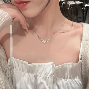 Detail shot of an elegant silver bow necklace with sparkling zircon pendants on a model