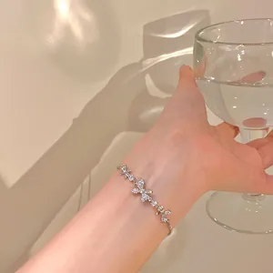 Detailed view of a delicate silver bow-knot bracelet with sparkling cubic zirconia on a wrist.