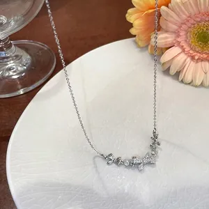 Close-up of elegant silver bowknot necklace with sparkling zircons on white plate