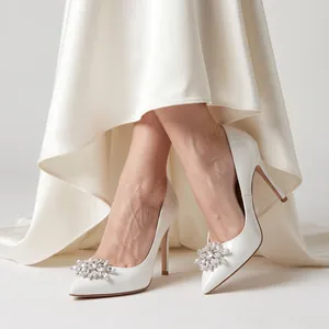 Close-up of elegant crystal flower shoe clips on white high-heeled bridal pumps.