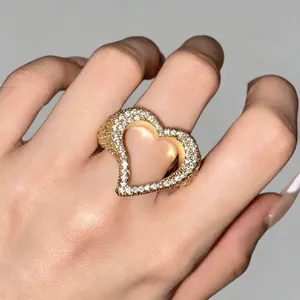 Detailansicht des hohlen Herzrings aus Gold mit glänzenden Zirkonia-Steinen auf der Hand