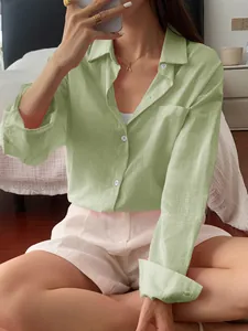 Detail of a women's casual light green long-sleeved shirt with pocket in home setting.