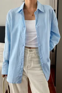 Detail of a light blue long-sleeved shirt with a relaxed holiday aesthetic