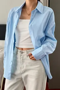 Detail showing the light blue linen-textured fabric and buttoned cuffs of the shirt.