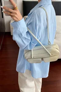 Detail shot of a light blue long-sleeved casual shirt paired with a stylish cream handbag