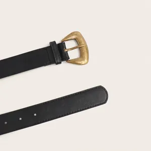 Gros plan d'une ceinture en similicuir noir avec une boucle en bronze de style vintage.