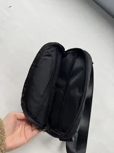 Internal detail view of black crossbody bag showing multiple zippered compartments and mesh pockets