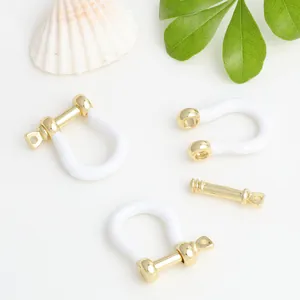 Close-up of white enamel gold-plated copper U-shaped horseshoe buckles for DIY jewelry
