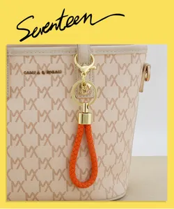 Detailed view of a hand-woven orange leather keychain with gold hardware on a designer bag