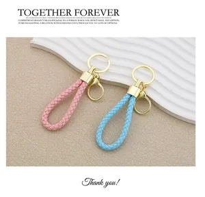 Detailed view of handmade braided leather keychains in pink and blue with gold hardware
