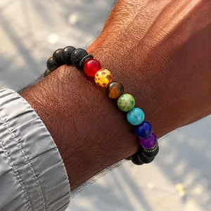 Macro view of natural lava stones and colorful chakra beads worn on a male wrist outdoors