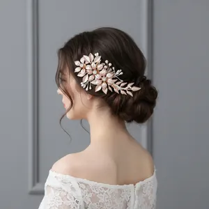 Detail view of a rose gold floral bridal hair clip with metal leaves and pearls.