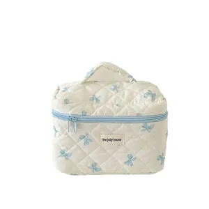 Trousse à maquillage matelassée blanche avec motif nœud bleu et poignée de transport