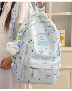 Détail montrant un sac à dos bleu clair à pois avec motifs d'ours et pendentif en peluche