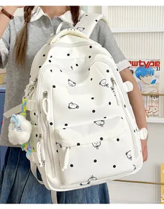 Vue détaillée du sac à dos blanc à pois avec motifs d'ours et un charme en peluche doux.