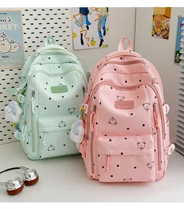 Vue détaillée de sacs à dos tendance rose et vert menthe à motif d'ours et pompons