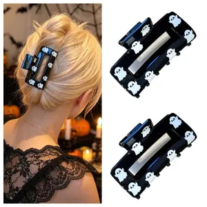 Close-up of black Halloween hair claw clip with playful white ghost prints