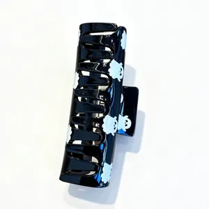 Detailed view of a glossy black hair claw clip with cute white ghost prints for Halloween