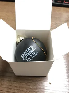 Detailed view of funny black Christmas ornament with white Santa slogan in a gift box