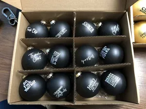 Funny matte black Christmas ornaments with rude sweary phrases in cardboard box
