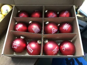 Detailed view of red matte Christmas baubles with funny rude English sayings in box